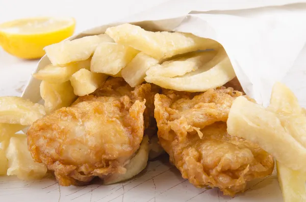Batatas fritas e peixe em um saco branco — Fotografia de Stock