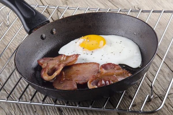 Fried egg and bacon in a pan — Stock Photo, Image