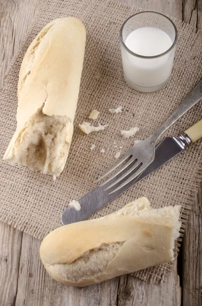 Baguette and glass milk on jute — Stock Photo, Image