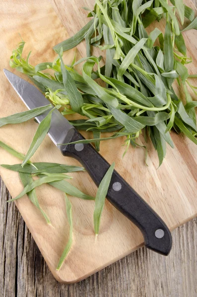 Ahşap tahta üzerinde tarhun ve mutfak bıçağı — Stok fotoğraf