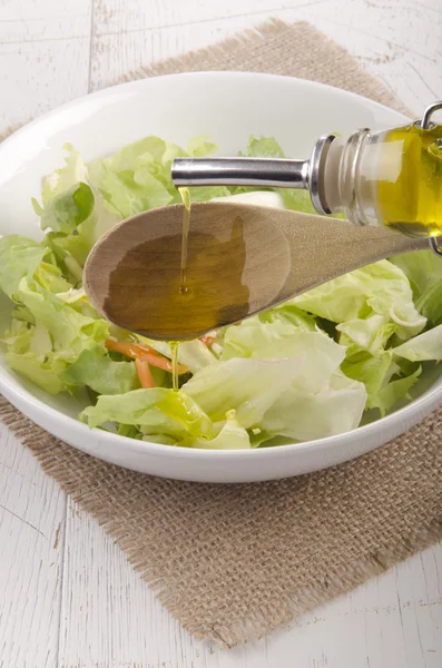 Olive oil in a bowl with salad — Stock Photo, Image