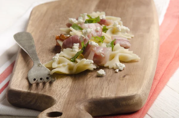 Farfalle nouilles sur une planche en bois — Photo