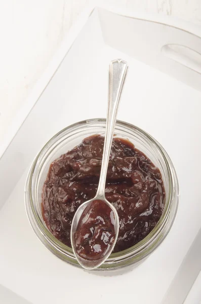 Glas met pruim jam en een kleine lepel — Stockfoto