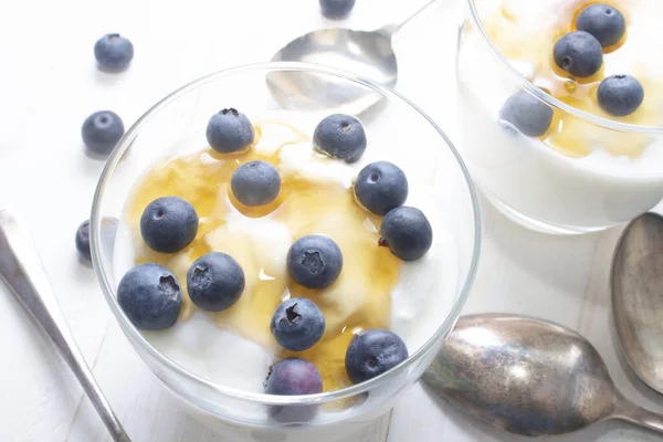 Griechischer Joghurt Mit Süßem Honig Und Ein Paar Blaubeeren Glas lizenzfreie Stockfotos