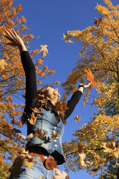 Mujer joven en el parque con hojas — Foto de Stock