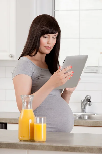 Vackra gravid kvinna med digital tablet — Stockfoto