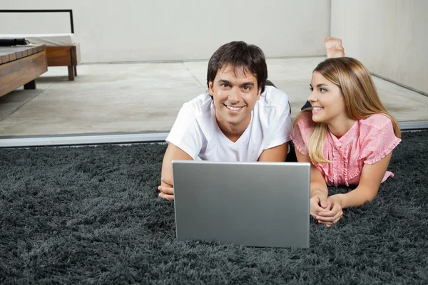 Casal com laptop no tapete — Fotografia de Stock