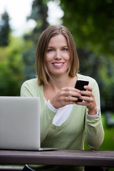 Aantrekkelijke vrouw in park met slimme telefoon — Stockfoto