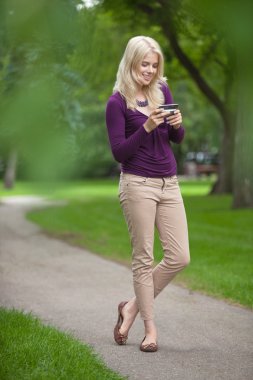 Parkta akıllı telefon kullanan kadın.
