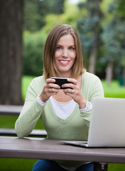 Kvinna anläggning cell telefonerna — Stockfoto