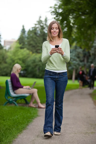 Mujer leyendo mensaje de texto en el parque — Foto de Stock