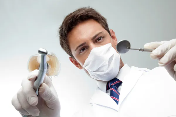 Dentiste tenant miroir incliné et perceuse — Photo