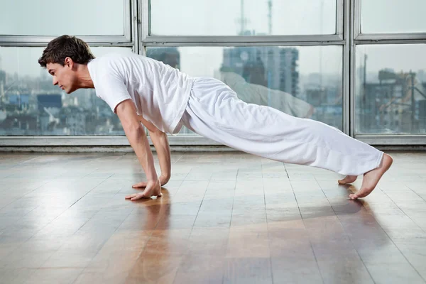 Молодой человек практикует йогу в спортзале — стоковое фото