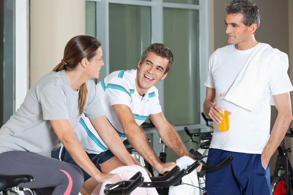 Man tittar på happy vänner utövar på spinning cykel — Stockfoto