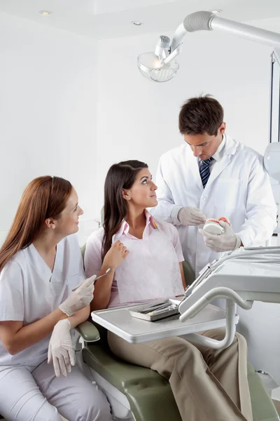 Стоматолог пояснює модель зубів пацієнту в клініці — стокове фото