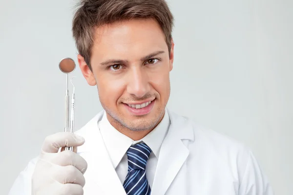 Dentista segurando espelho angulado e carver — Fotografia de Stock