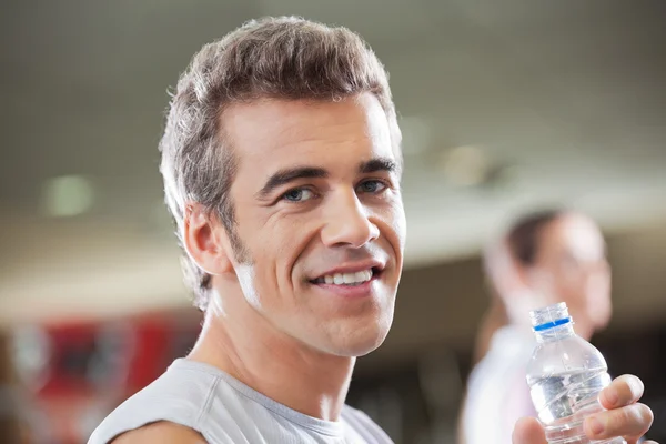 Mann hält Wasserflasche in Fitnessstudio — Stockfoto