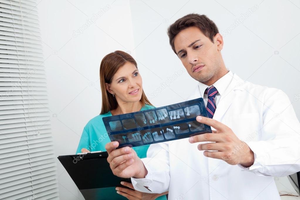 Doctor And Assistant Analyzing Patient's Report