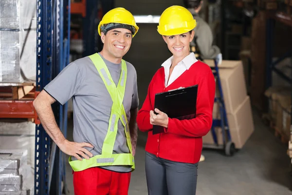 Vorgesetzter hält Klemmbrett mit Vorarbeiter im Lager — Stockfoto