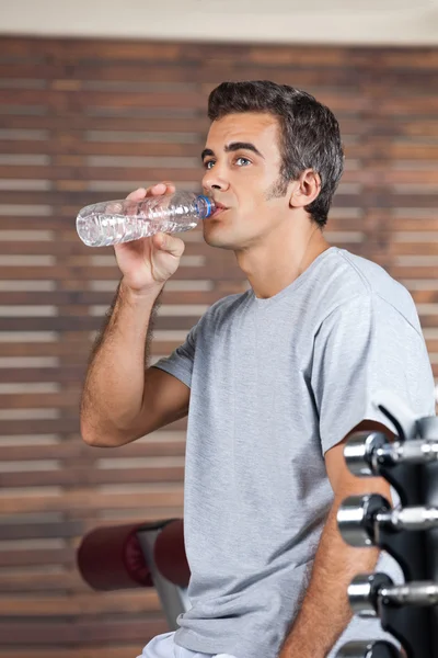 Mann trinkt Wasser aus Flasche in Fitnessstudio — Stockfoto