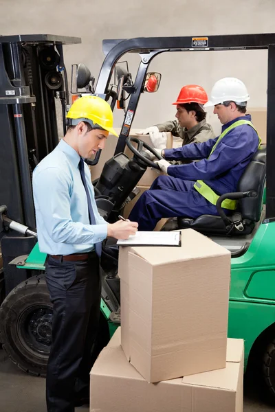 Toezichthouder met voormannen werken in magazijn — Stockfoto