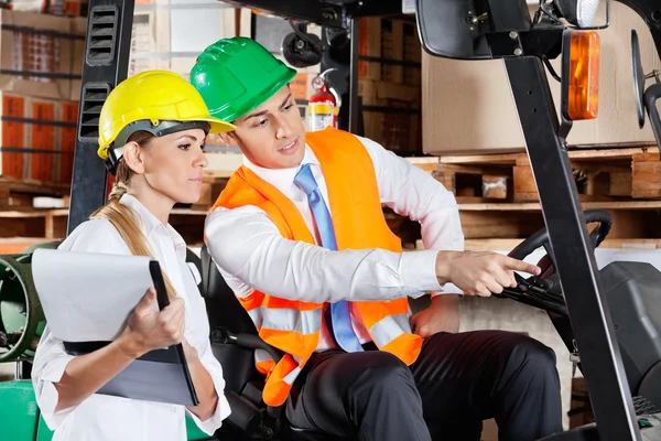 Männlicher Vorgesetzter zeigt Kollegen im Lager etwas — Stockfoto