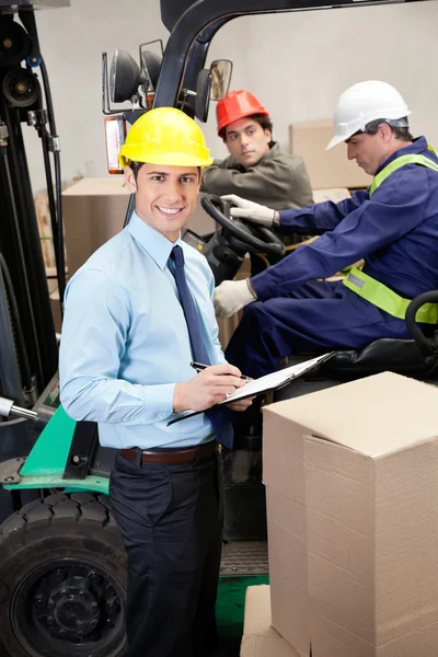 Supervisore con i capisquadra che lavorano al magazzino Foto Stock