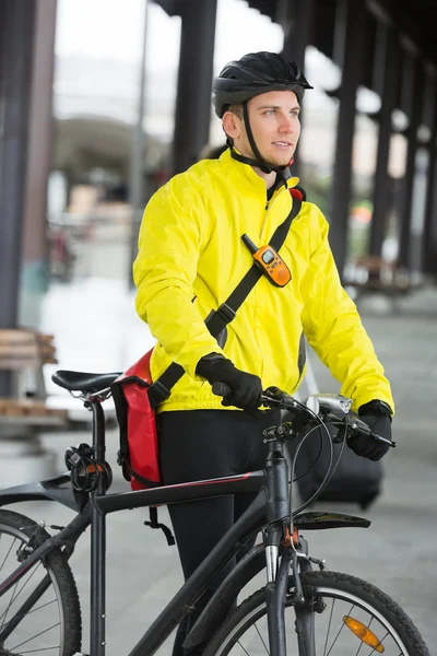 Jeune homme avec vélo et sac regardant loin — Photo