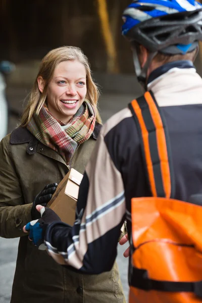 Lächelnde junge Frau erhält Paket von Kurierzusteller — Stockfoto