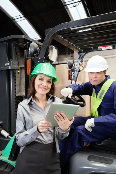 Kadın yönetici ve forklift sürücüsü dijital tablet ile — Stok fotoğraf