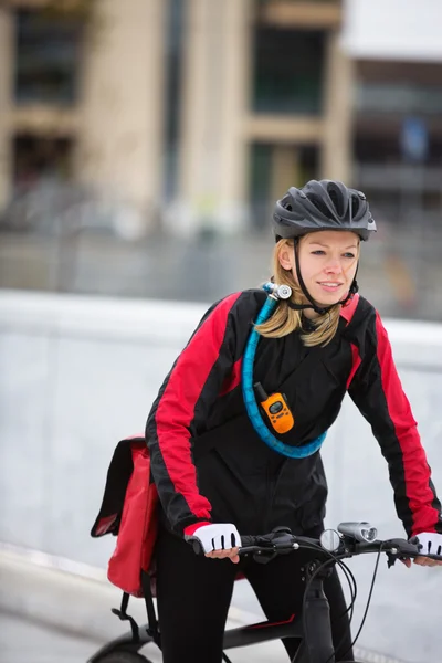 Молодая женщина на велосипеде с курьерской сумкой — стоковое фото