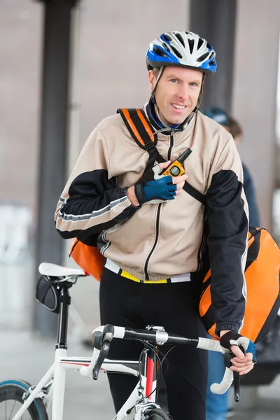 Mannelijke wielrenner met courier tas met behulp van walkie-talkie — Stockfoto