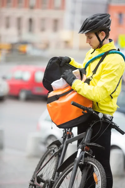 Giovane ciclista maschile che mette il pacchetto nella borsa del corriere — Foto Stock