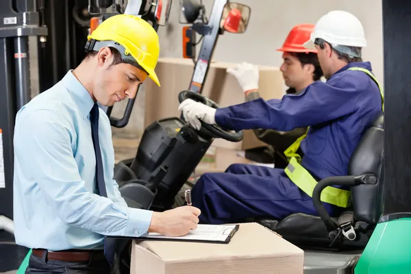 Supervisor masculino escrevendo na área de transferência no armazém — Fotografia de Stock