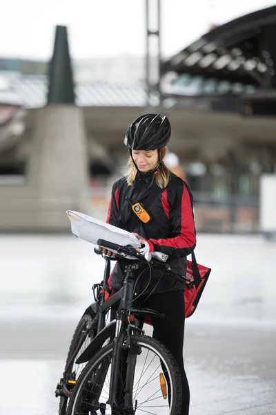 Cycliste femelle avec sac de courrier et paquet sur la rue — Photo