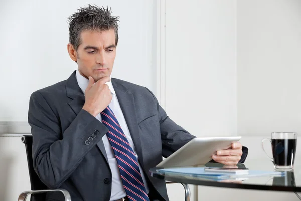 Empresário contemplativo usando tablet digital no escritório — Fotografia de Stock