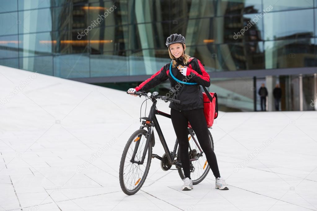Female Cyclist With Courier Delivery Bag Using Walkie-Talkie
