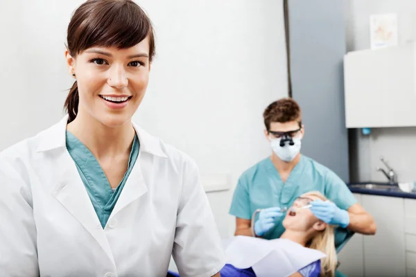 Vrouwelijke assistent met tandarts die werkt op de achtergrond — Stockfoto