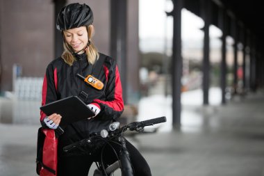 Female Cyclist With Courier Bag Using Digital Tablet clipart