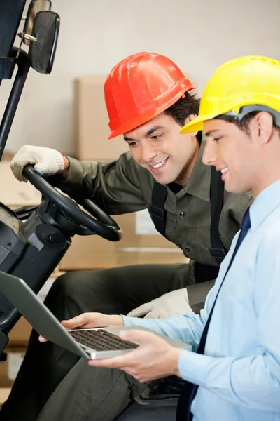 Mannelijke toezichthouder en vorkheftruck stuurprogramma met behulp van laptop — Stockfoto