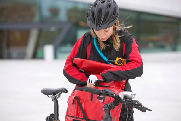Kvinnlig cyklist tittar genom kurir leverans väska — Stockfoto