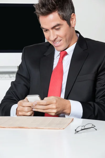 Empresario usando el teléfono celular en el escritorio — Foto de Stock