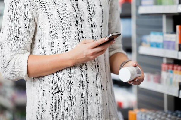 Mujer escaneando botella con teléfono Smar — Foto de Stock