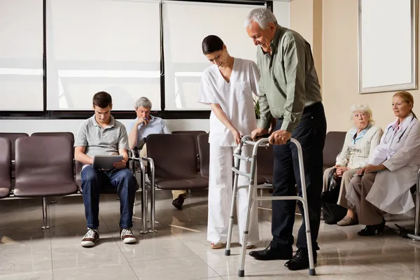 Uomo aiutato dall'infermiera a camminare Zimmer telaio — Foto Stock