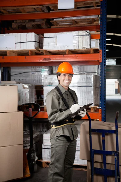 Toezichthouder schrijven op Klembord in magazijn — Stockfoto