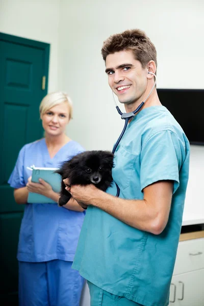 Veterinarian Doctor Carrying A Dog With Female Nurse Holding Cli — Stock Photo, Image