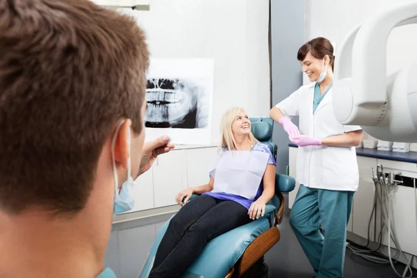 Dentista examinando imagen de rayos X con asistente femenino de la comunicatina — Foto de Stock