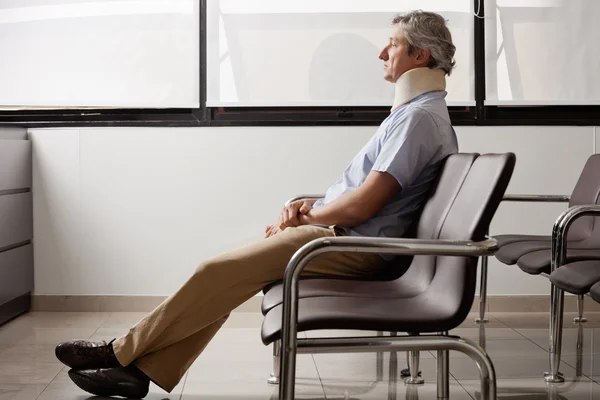 Hombre con lesión en el cuello esperando en el vestíbulo —  Fotos de Stock