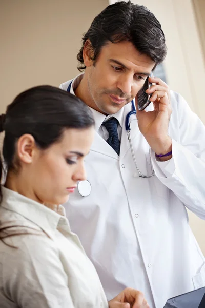 Médecin assistant à l'appel tout en étant debout avec un collègue — Photo