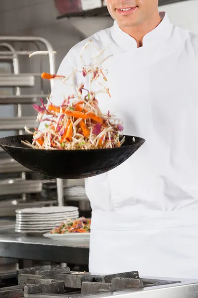 Chef lançando legumes em wok — Fotografia de Stock